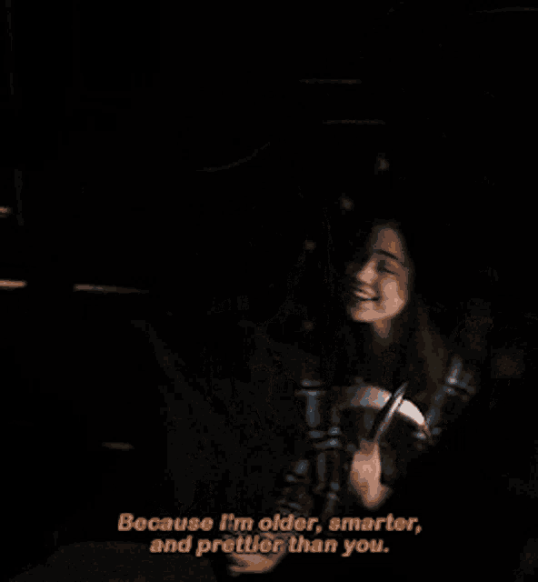 a woman is sitting on a bed and says because i 'm older smarter and prettier than you ..