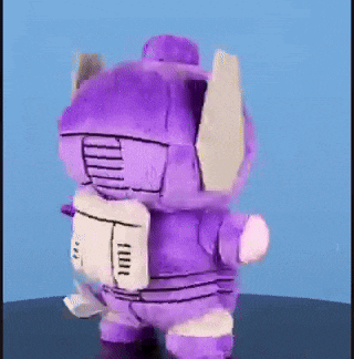 a stuffed toy of a robot with a yellow eye is standing on a table .