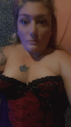 a woman with a butterfly tattoo on her chest is wearing a red and black corset