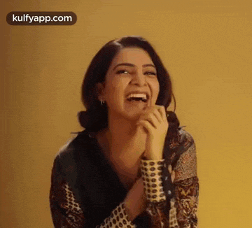 a woman is laughing with her hands on her face and covering her mouth with her hands .