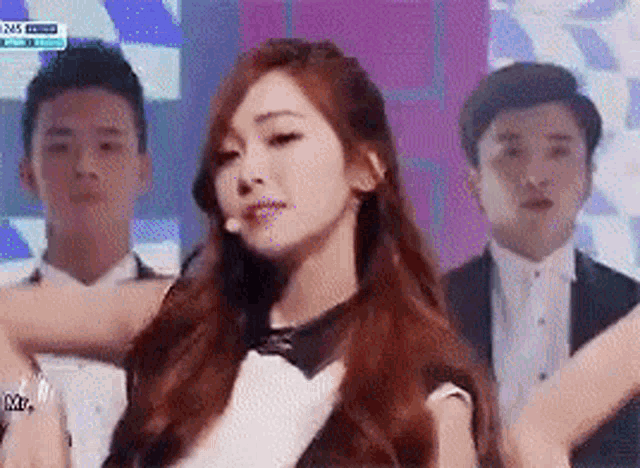 a woman with long red hair is dancing in front of a group of men .