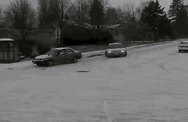 a black and white photo of a car driving through the snow .