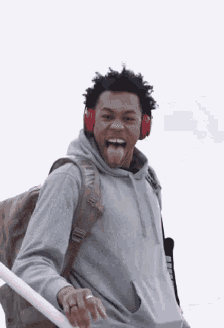 a man wearing headphones and a backpack sticks his tongue out