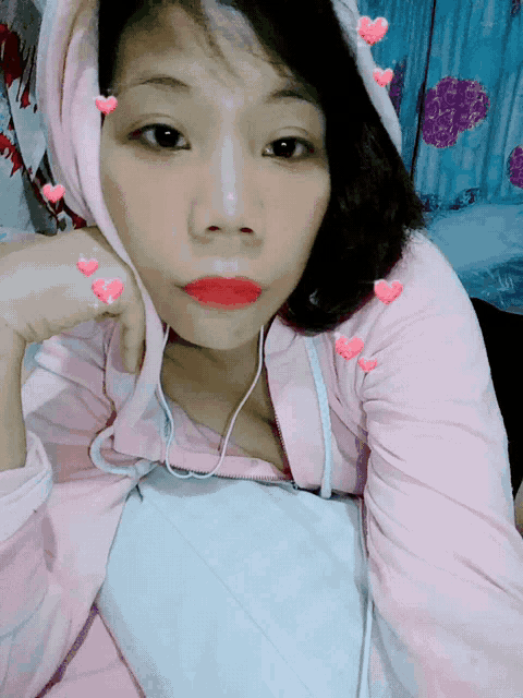 a girl wearing a pink hoodie with hearts on her face