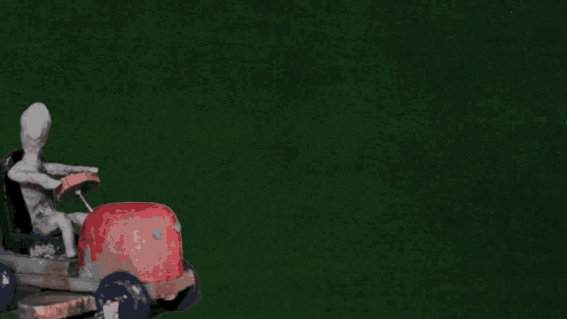 a statue of a man sitting in a lawn mower with a green background