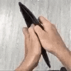 a person is holding a pen in their hands and using it to write on a piece of paper .