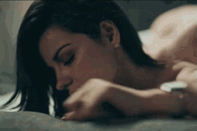 a woman is laying on a bed with her head on a pillow .