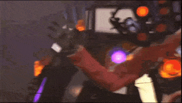 a man in a red jacket and black gloves is standing in front of a halloween decoration and waving .