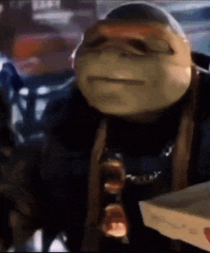 a ninja turtle is holding a box of pizza in his hand