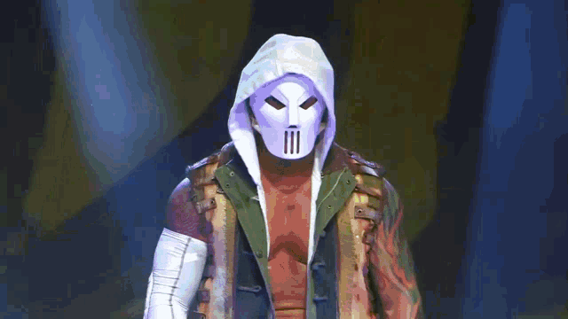 a man wearing a mask and a hooded jacket stands in front of a yellow background