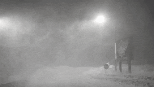 a black and white photo of a snowy road at night