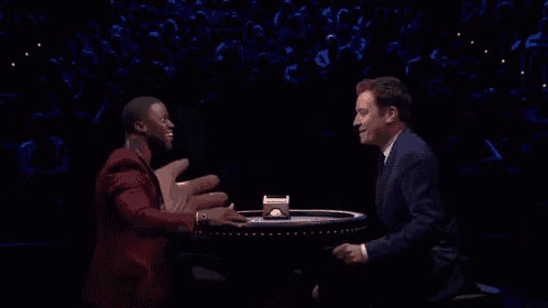 a man in a suit and tie is giving a high five to another man .