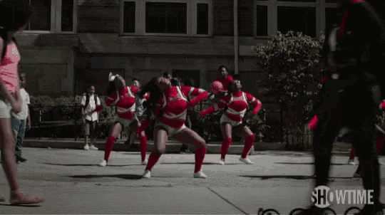 a group of cheerleaders are dancing in front of a building with showtime written in the corner