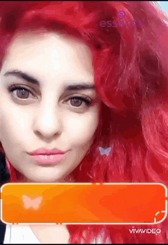 a close up of a woman 's face with red hair and a butterfly on her ear