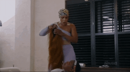 a woman is putting a wig on a man 's head ..