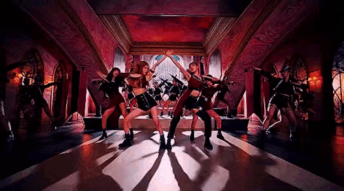 a group of dancers are dancing in a room with a red ceiling .
