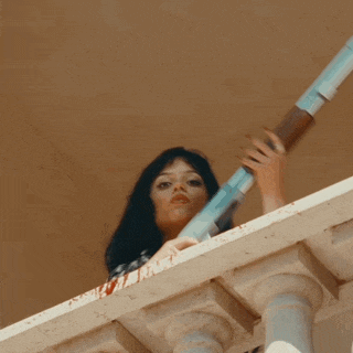 a woman stands on a balcony looking down
