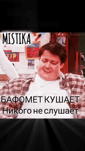 a man in a plaid shirt sits in front of a refrigerator with the word mistika written on it