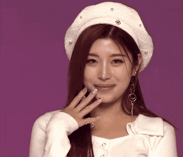 a woman wearing a white hat with pearls on it is smiling