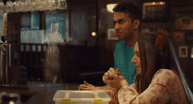 a man and a woman are sitting at a bar with a box on the table