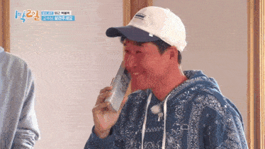 a man wearing a bandana sweatshirt and a white hat is talking on a cell phone .
