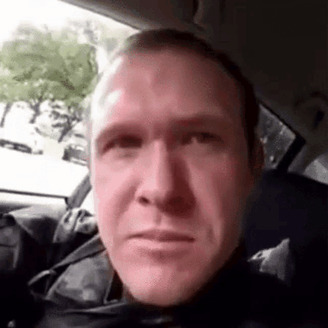 a man is sitting in the back seat of a car and making a face .