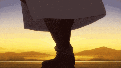 a person 's feet are shown in front of a sunset with mountains in the background
