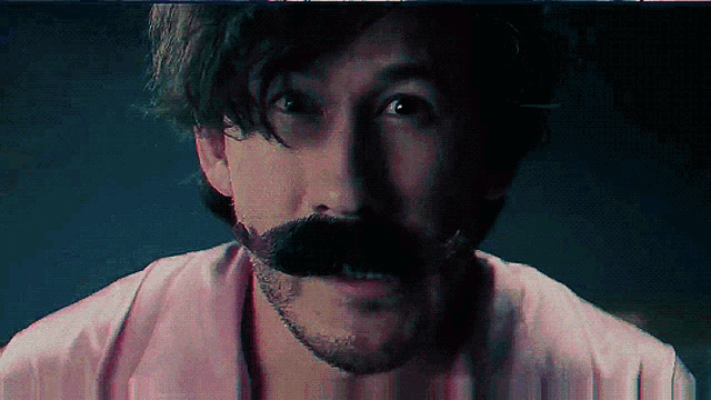 a man with a beard and mustache wearing a pink shirt