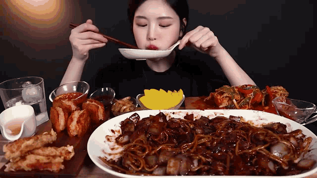 a woman is eating a plate of food with chopsticks and a spoon