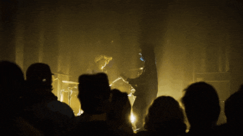 a group of people watching a band on stage in the dark
