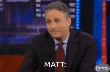 a man in a suit and tie is sitting on a stage with his hands on his face and says matt .