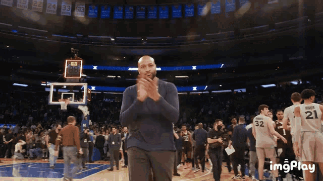 a basketball player with the number 21 on his jersey applauds
