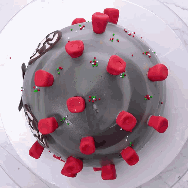 a cake decorated to look like a virus with red marshmallows and sprinkles