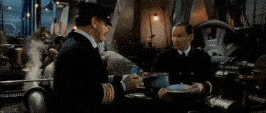 a man in a captain 's hat is pointing at something in a factory .