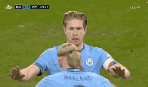 two soccer players are on a field and one has the word etihad on his jersey