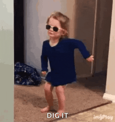 a little girl wearing sunglasses is dancing on the floor .