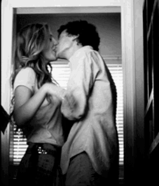 a man and woman are kissing in a doorway