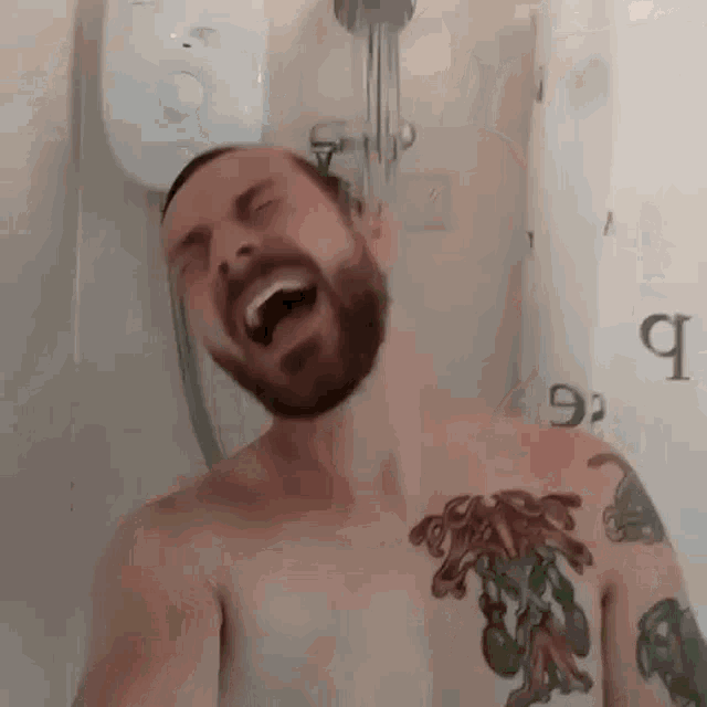 a shirtless man with a tattoo on his chest is taking a selfie in a shower .