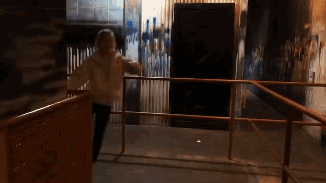 a woman in a pink jacket is dancing in a room with graffiti on the wall