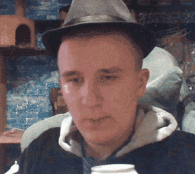 a man wearing a hat and a hoodie is looking at something