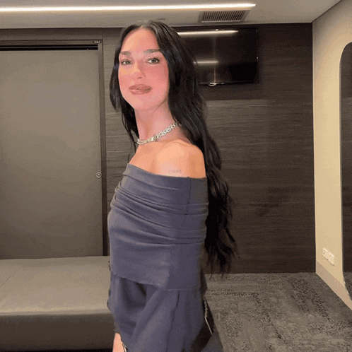 a woman wearing a blue off the shoulder top has a tattoo on her shoulder that says love
