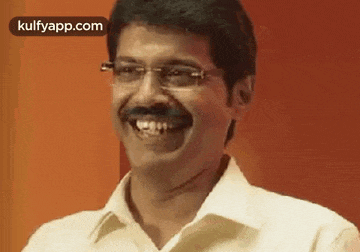 a man wearing glasses and a mustache is smiling .