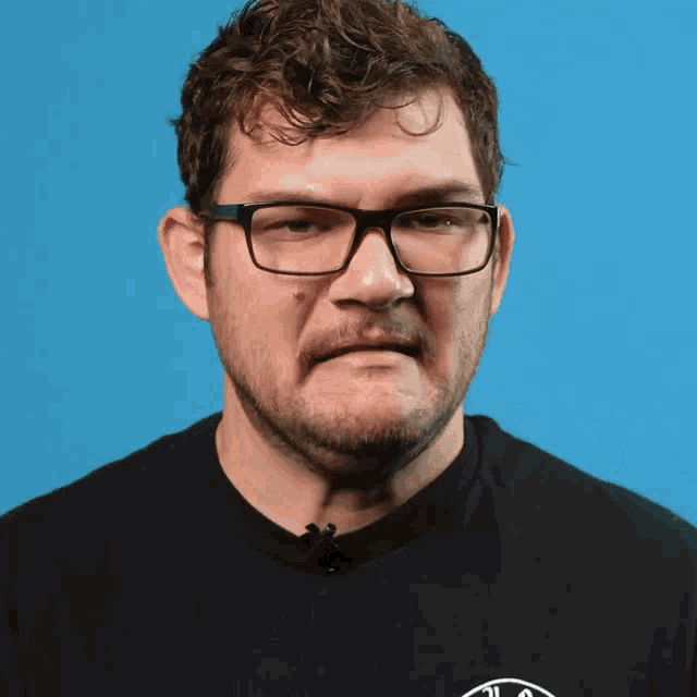 a man wearing glasses and a black shirt with a white circle on it