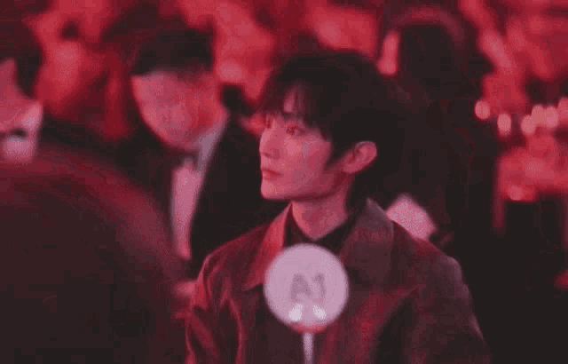 a young man is sitting at a table in a crowd of people at a party .