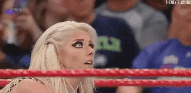a woman is standing in a wrestling ring looking at the camera .