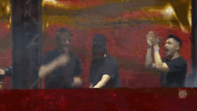 a group of men are dancing on a stage with a red background .