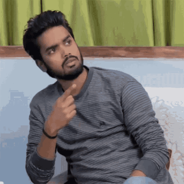 a man with a beard is sitting on a couch and making a face