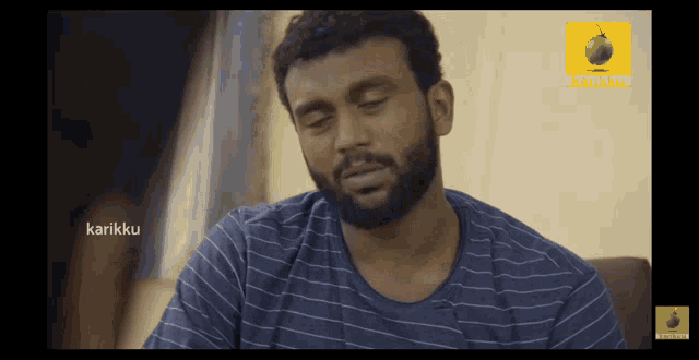 a man with a beard is sitting in front of a screen that says ' karikku ' on it