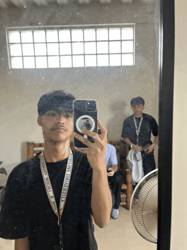 a man taking a selfie in front of a mirror with a lanyard around his neck that says ytb university