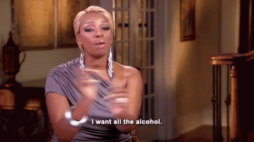 a woman in a gray dress is sitting in a chair and talking about alcohol .